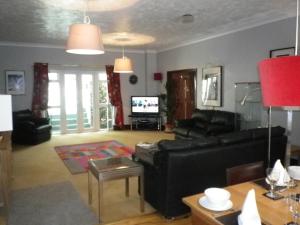 a living room with a black couch and a tv at Bridge Hall Apartments in Weston-super-Mare