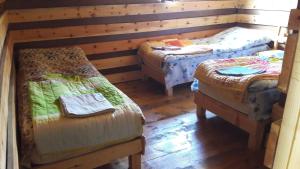 three beds in a room with wooden walls and wooden floors at Guesthouse Javakhe in Omalo