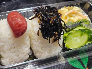 a plastic container with rice and a hot dog and vegetables at 民宿たけだ家 in Saka