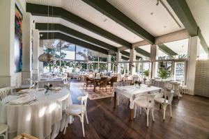 un restaurante con mesas y sillas blancas y ventanas en H & R Estrella del Bajo Carrión, en Villoldo