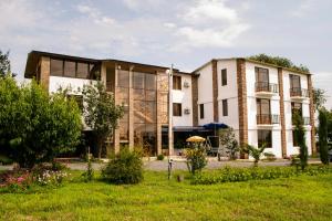 a large building with glass windows and a yard at Shaloshvili's Cellar Hotel in Shilda