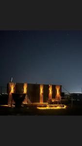 Un edificio con luces en el frente por la noche. en Red stone Glamping, en Taldykorgan