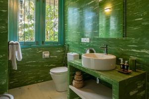 a green bathroom with a sink and a toilet at Monara - Tangalle in Tangalle +91 photos