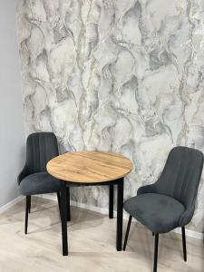 two chairs and a wooden table in front of a wall at Уральская 45А in Kostanay