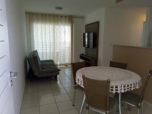sala de estar con mesa, sillas y TV en Natture Condomínio Clube, en Natal