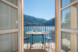 a balcony with a table and chairs and a view of the water at Apartments At the Pier Of Brienno - The House Of Travelers in Brienno