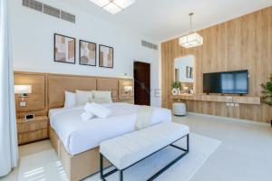 a bedroom with a large white bed and a tv at Elegant 4BR Villa with Arabian Gulf, Mountain and Community Views, Assistant Room and Heated Pool, Al Dana Island, Fujairah by Deluxe Holiday Homes in Fujairah +30 photos