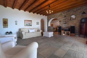 a living room with a couch and a stone wall at Tinos Sky View Villa in Arnados