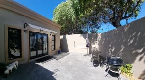 a patio of a house with a dog and a grill at Sunset Getaways in Cape Town