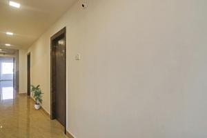 a hallway with a white wall and a door at Townhouse De Alphabet Hotel in Hyderabad