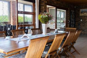 a wooden table with chairs and a vase with flowers at White Shark Guest House in Gansbaai +62 photos