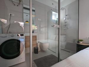 a bathroom with a shower and a washing machine at Cowshed w Floor Heating in Ugly Duckling Courtyard in Zagreb +13 photos
