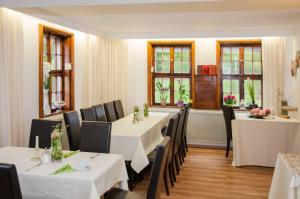 un restaurante con mesas y sillas blancas y ventanas en Apart Hotel Paradies en Bad Salzschlirf