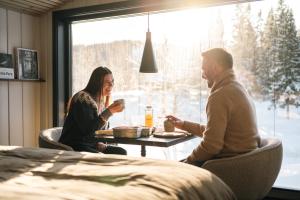 a man and woman sitting at a table in front of a window at Ådalsvollen Retreat -Go Wild for a While, Private Nature Getaway in Verdal