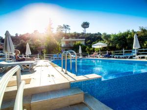 a swimming pool with people sitting on chairs and umbrellas at Flower Hotel Patara in Patara