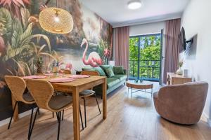 オルシュティンにあるApartamenty Grzegorzewskaのダイニングテーブルとフラミンゴの絵が飾られたリビングルーム