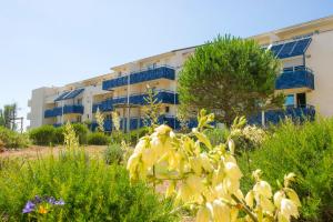 a building with blue balconies and flowers in a garden at Residence Lacanau Bleu Marine - maeva Home in Lacanau