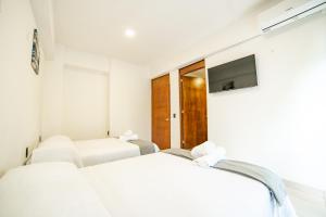 two beds in a room with a tv at Hotel Catedral Jojutla in Jojutla