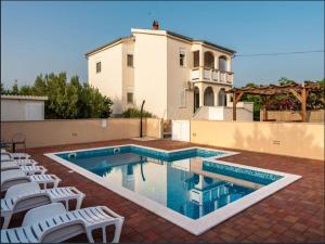 a swimming pool with white chairs and a house at Villa in Vrsi with Pool near Sandy Beach in Vrsi