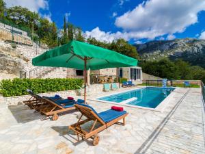 ein Pool mit zwei Stühlen und einem grünen Sonnenschirm in der Unterkunft Villa Falcon Rook - Four-Bedroom Villa with Terrace and Swimming Pool in Dubravka