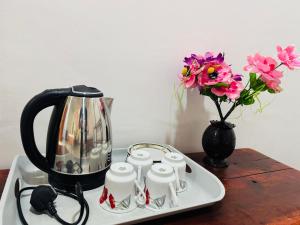 a tea kettle and a vase with flowers on a table at Green Lake Sigiriya in Sigiriya