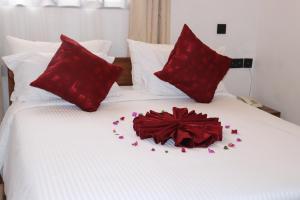 a bed with red pillows and a flower on it at Blue Junction Eco Lodge in Arusha