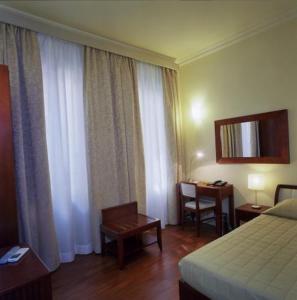 Habitación de hotel con cama, mesa y escritorio. en Hotel Agathae, en Catania