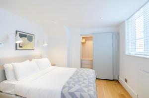 a white bedroom with a large bed and a window at Native Fulham in London