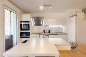 a white kitchen with a large white counter top at Le Cocon de Beaumont - T3 Cozy in Beaumont