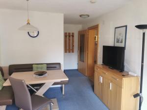 a living room with a table and a tv at Haus Bergmassiv in Lermoos