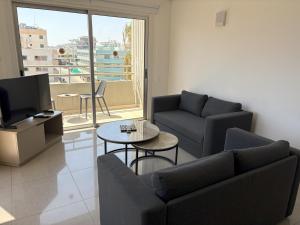 a living room with a couch and a tv and a table at Sunflower Hotel Apartments in Larnaca