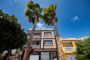 a building with two palm trees in front of it at Marody House Vacacional in Granadilla de Abona