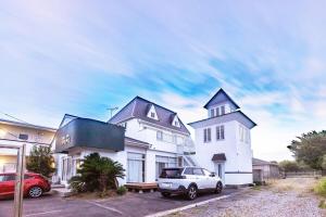 a white house with a car parked in a parking lot at PiPi Vacation Rental in Ichinomiya