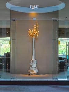 a glass wall with a vase with a tree in it at Cidnay - Hotel & Executive Center in Santo Tirso