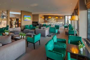 a lobby of a hotel with green chairs and tables at Cidnay - Hotel & Executive Center in Santo Tirso +74 photos