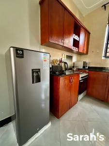 a kitchen with a stainless steel refrigerator and wooden cabinets at Sarahs in Kampala