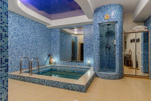 a blue tiled bathroom with a tub and a shower at Gallery Hotel Gintama in Kyiv