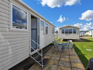 a patio with a table and chairs next to a trailer at 9 Fairway, Hopton Holiday Park - Three bedroom, sleeps 6, kitchen, lounge and dining area - Minimum 3 night breaks in Hopton on Sea