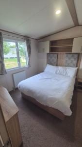 a bedroom with a large bed and a window at Hot tub retreat, at Tattersall Lakes caravan in Tattershall