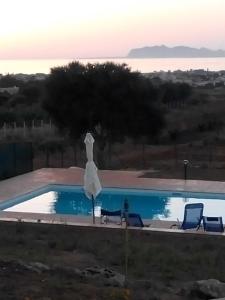 a swimming pool with two chairs and a white umbrella at Panorama Casa Vacanze in Marsala