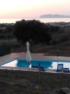 basen z 2 krzesłami i białym parasolem w obiekcie Panorama Casa Vacanze w mieście Marsala