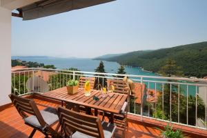 um deque com uma mesa de madeira e cadeiras numa varanda em Ana Apartment em Rabac