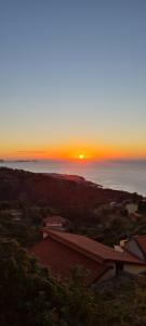 a sunset over the ocean with a house in the foreground at Refúgio das Regadinhas in Santa Cruz