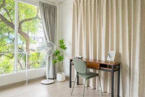 a desk and a chair in a room with a window at Glow House Sukhumvit 54 in Bangkok