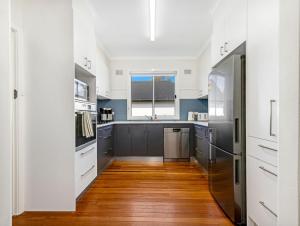 a kitchen with stainless steel appliances and wood floors at Beachfront Escape Relaxing Getaway in Batehaven in Sunshine Bay