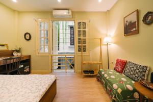 une chambre avec un lit, un canapé et une fenêtre dans l'établissement Anchie Vintage Homestay - Train Street Hanoi, à Hanoï