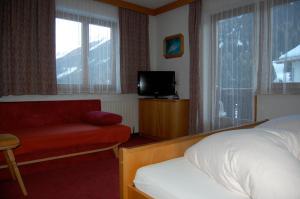 Habitación de hotel con cama, silla y TV en Haus Oberland, en Sankt Anton am Arlberg