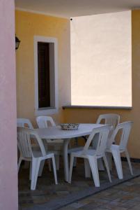una mesa blanca con sillas blancas alrededor en La dimora del Murales - Holiday home, en Badesi