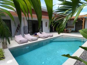 una piscina con sedie a sdraio e una casa di Villa ANSEJU Tranquillité, Jardin Tropical & 3 Chambres Spacieuses a Hua Thanon Beach