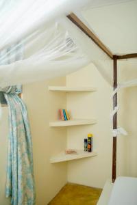a bedroom with a bed with a canopy and shelves at Low budget double room in Paje in Paje